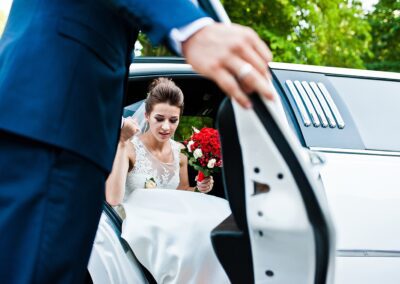 A bride stepping out of a white limousine on her wedding day