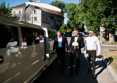 Men in tuxedos standing by limo