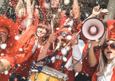 A cheerful group of people in red shirts and hats celebrating together with smiles and excitement